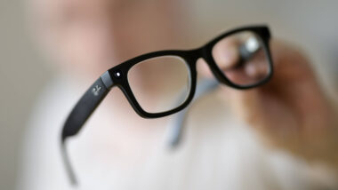Mensch hält Brille in die Kamera