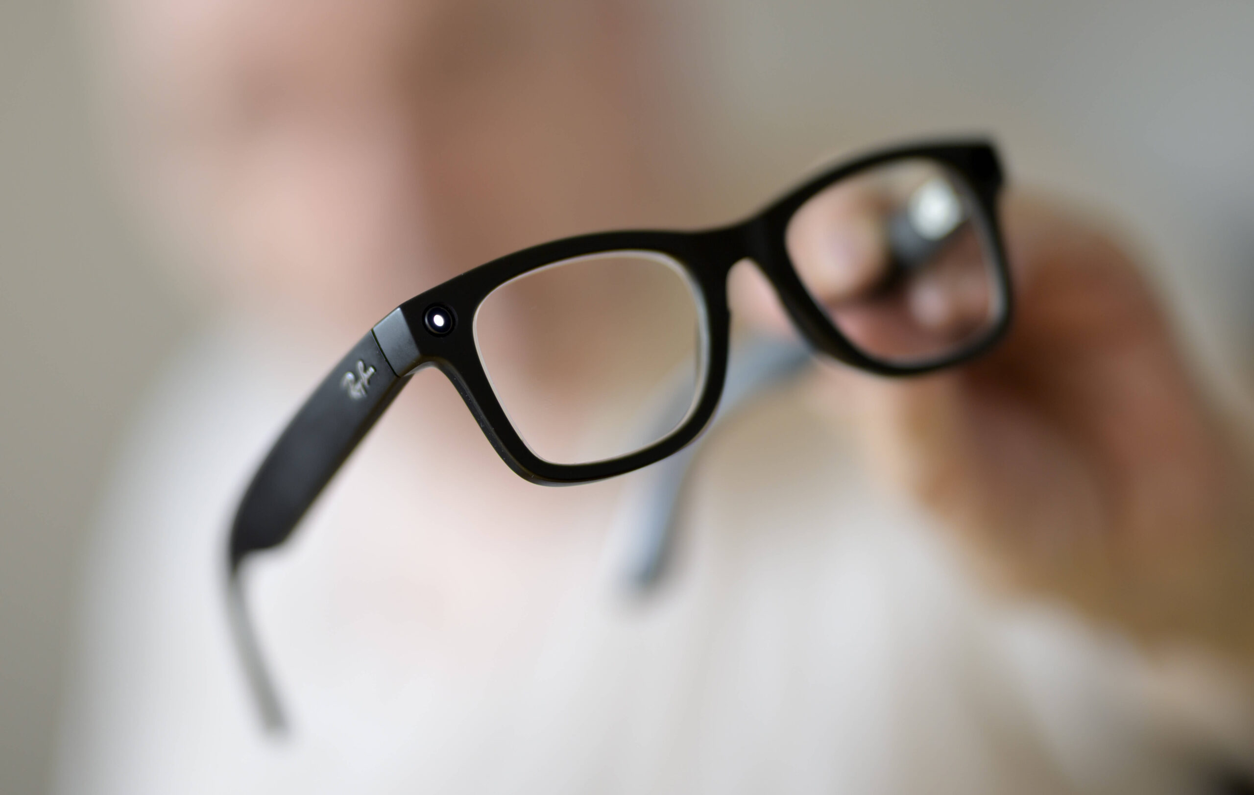 Mensch hält Brille in die Kamera