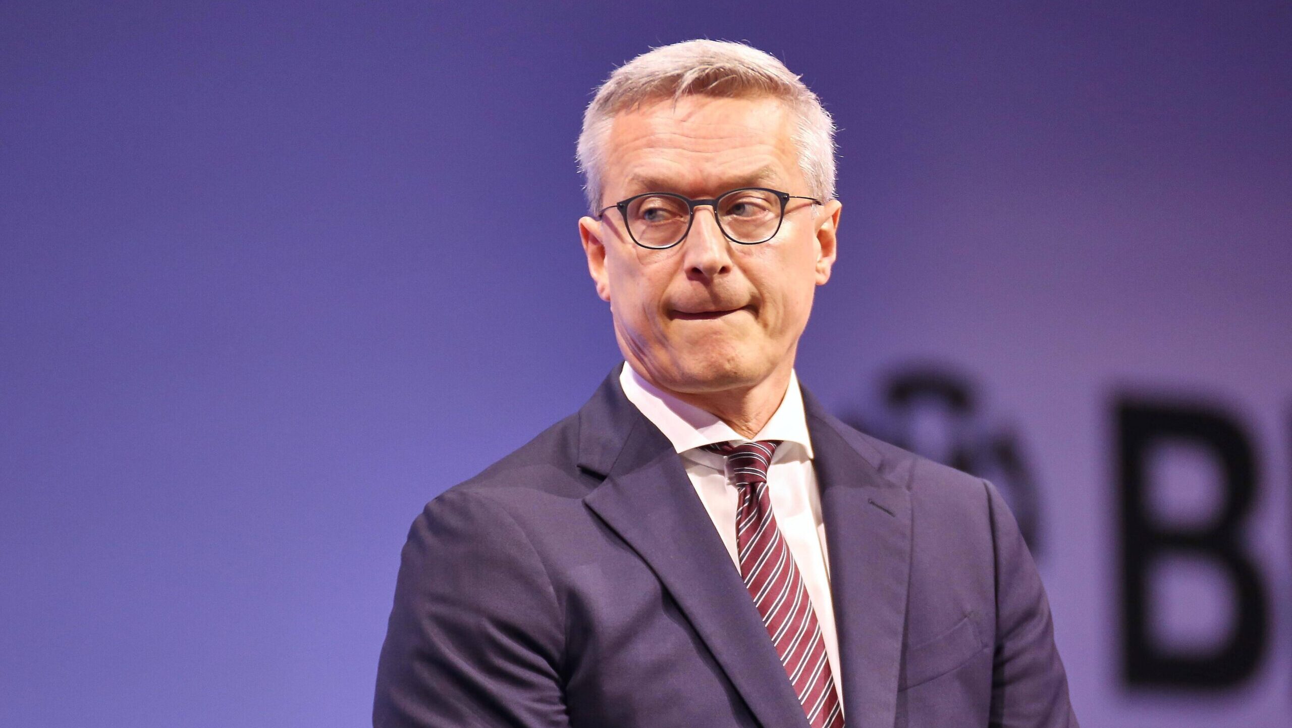 Karsten Wildberger vor einer blauen Leinwand, er guckt zur Seite