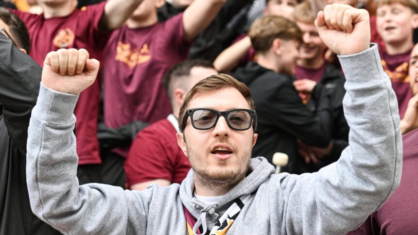 Fußballfan mit nach oben gerissenen Armen und Überwachungsbrille im Gesicht