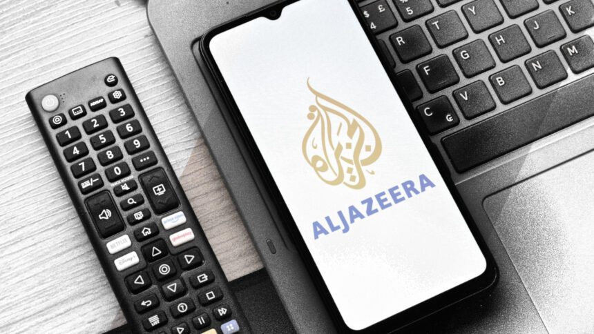 Eine Fernbedienung, einen Laptop-Tastatur, ein Smartphone mit Logo von Al Jazeera.