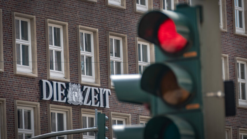 Rote Ampel vor einem Haus, auf dem ein Logo mit der Aufschrift "Die Zeit" hängt
