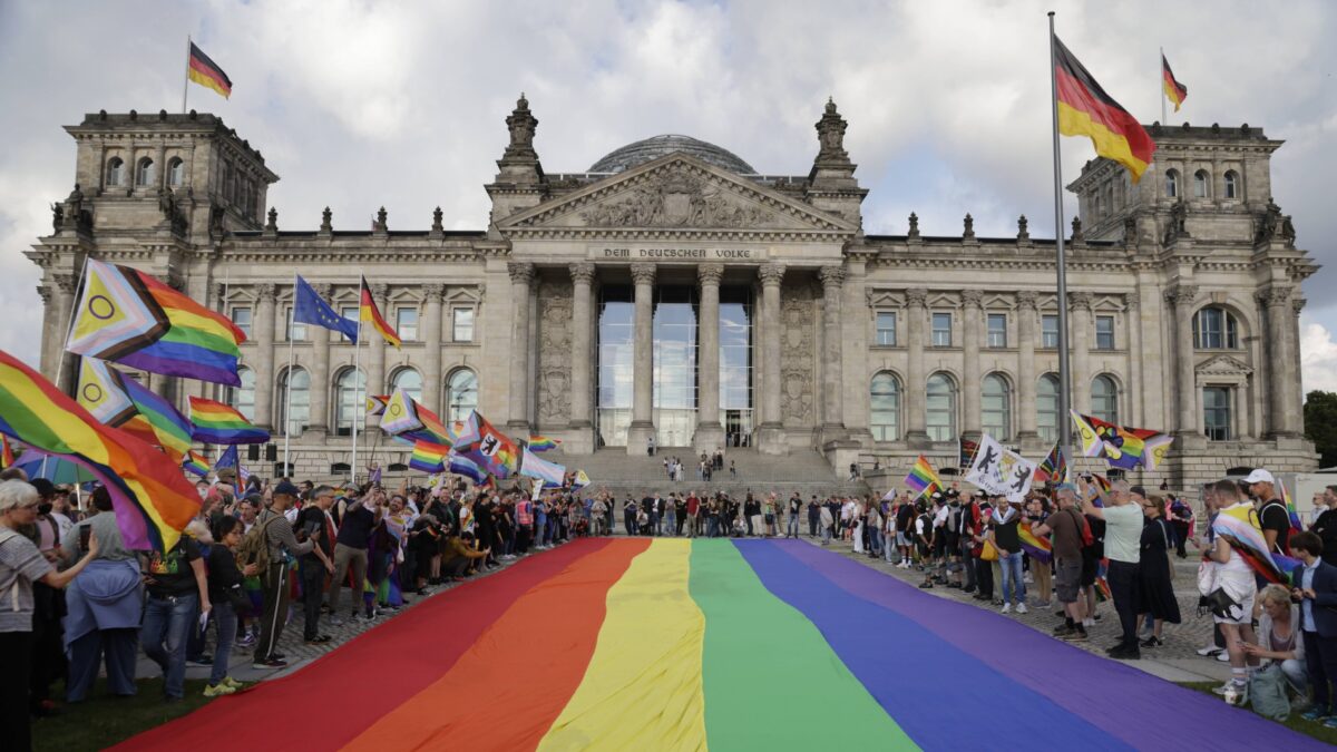 Der Bundestag, davor viele Menschen, die Regenbogenflaggen halten.