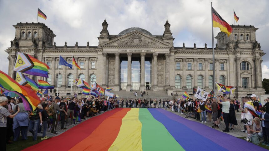 Der Bundestag, davor viele Menschen, die Regenbogenflaggen halten.