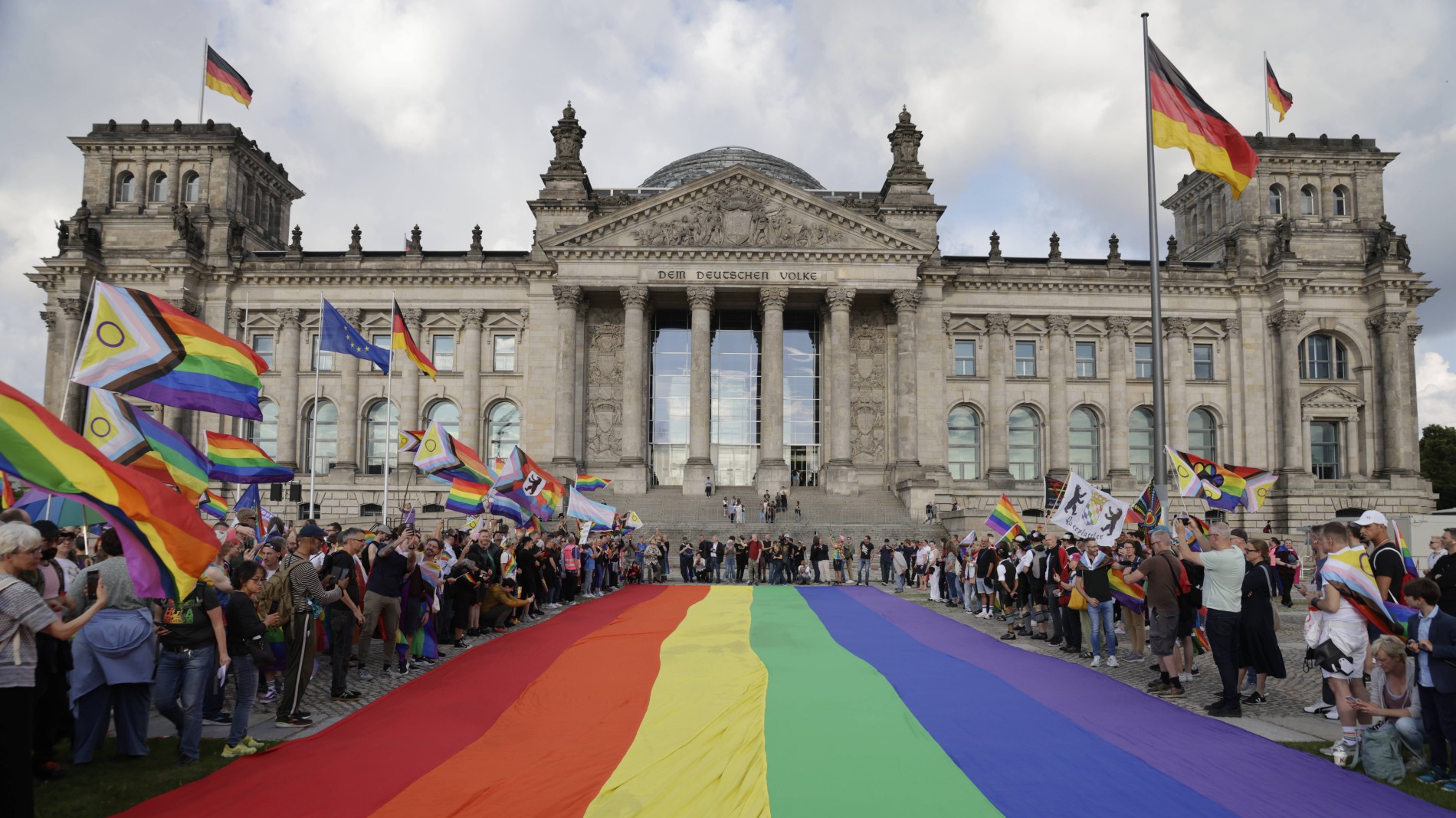 Der Bundestag, davor viele Menschen, die Regenbogenflaggen halten.