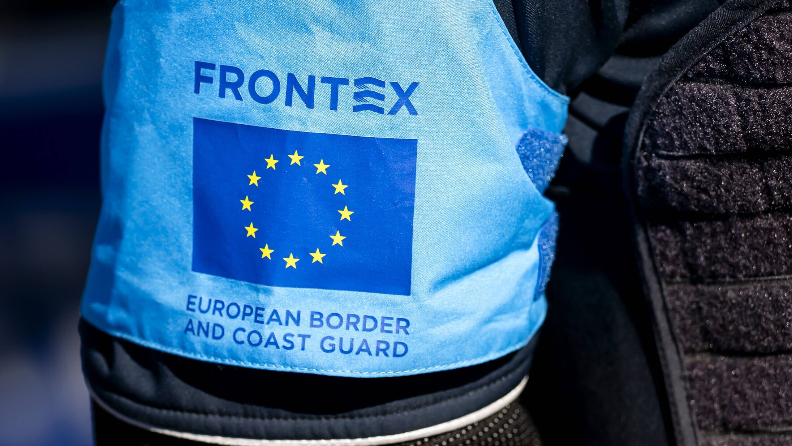 Mensch mit hellblauer Frontex-Weste von hinten fotografiert