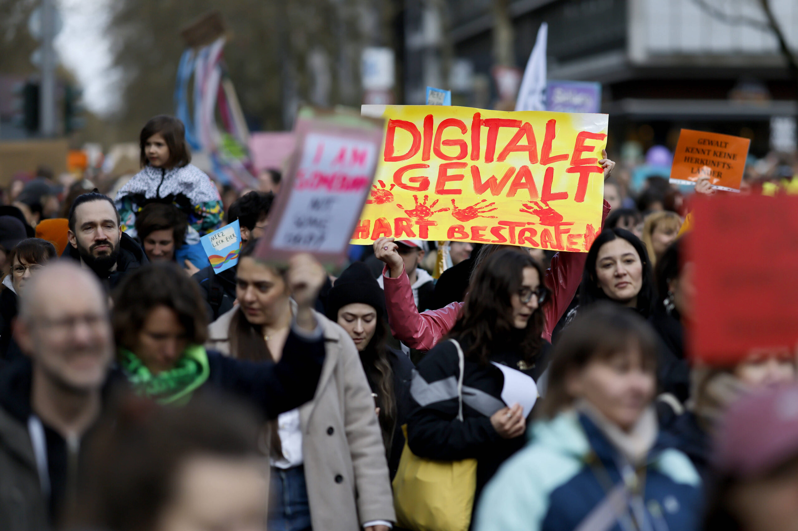 Eine Demo von vorn fotografiert, jemand trägt ei Schild "Digitale Gewalt härter bestrafen".