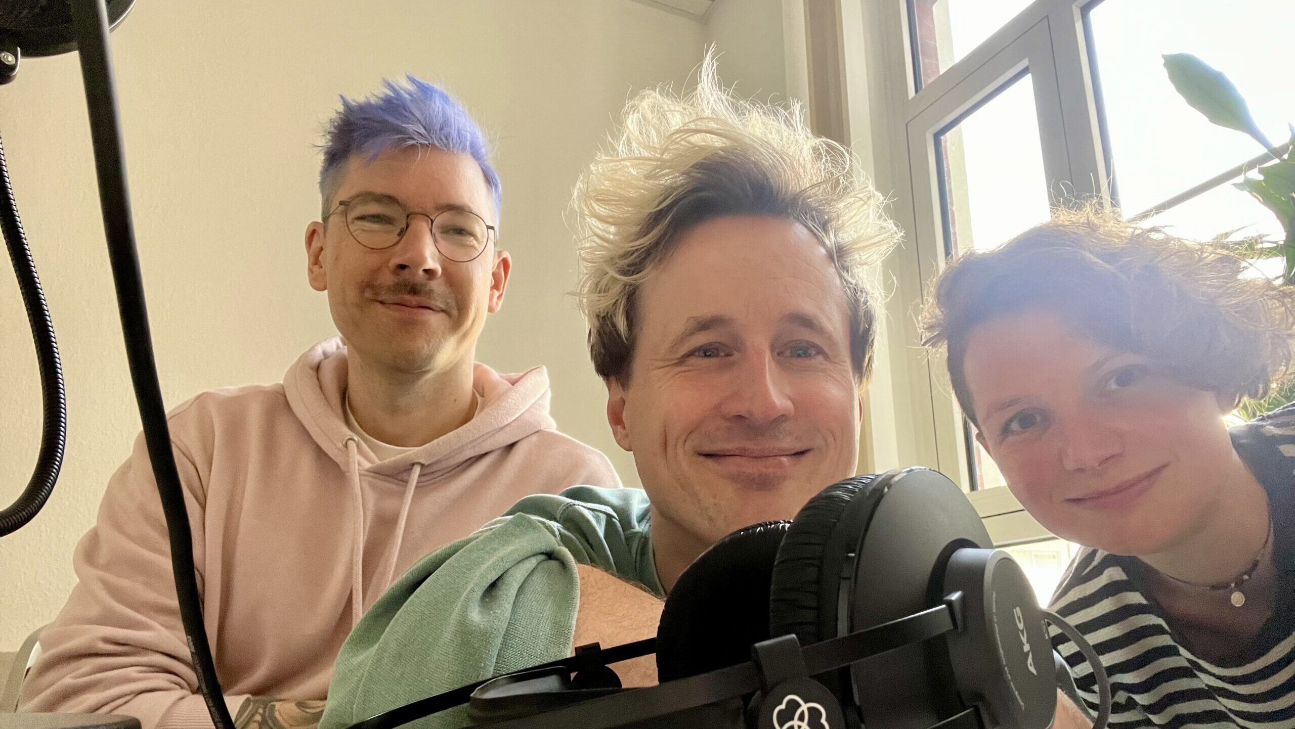 Drei Menschen mit Podcast-Equipment